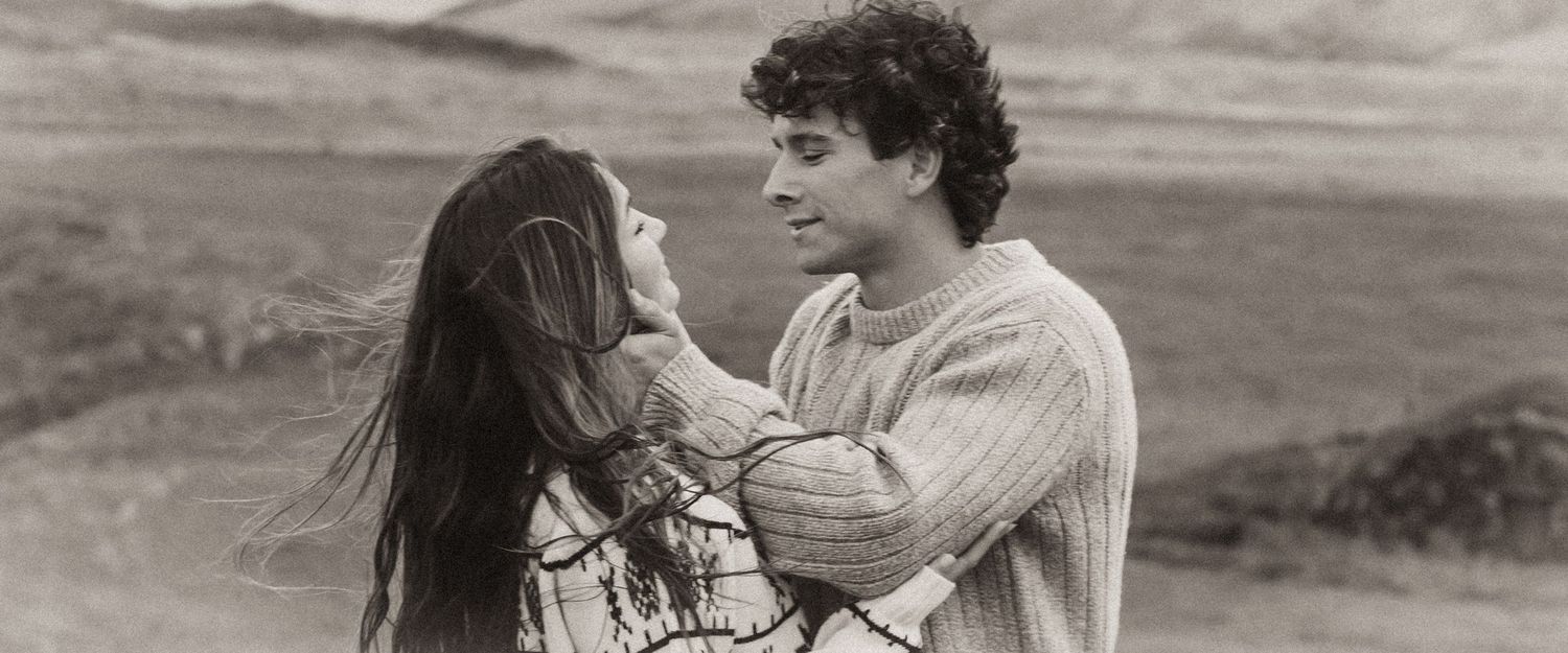 A panoramic black and white shot shows two people sharing a tender moment in nature.