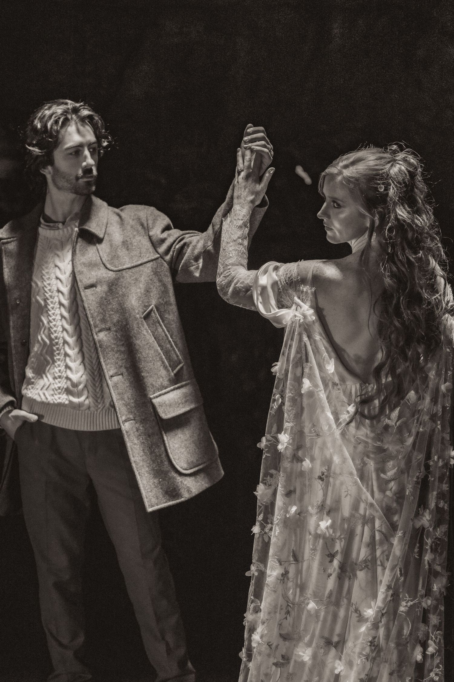 A dramatic black and white photo of two dancers in vintage attire performing an elegant dance pose together.