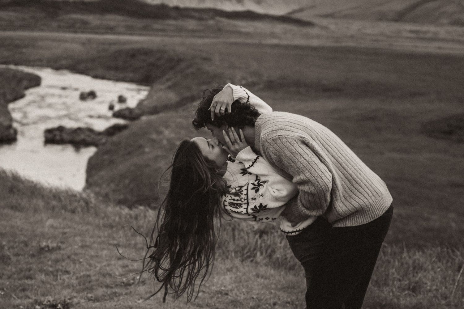 Black and white photo of intimate moment with winding river valley in background.