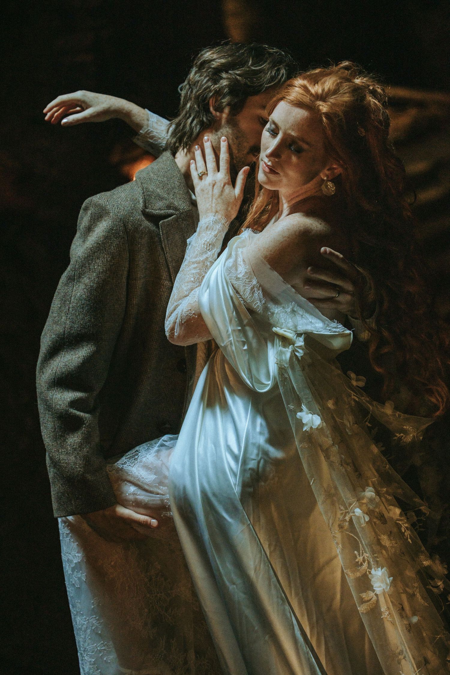 Ethereal romantic portrait of a couple in vintage attire with a woman in a flowing white dress and delicate lace.