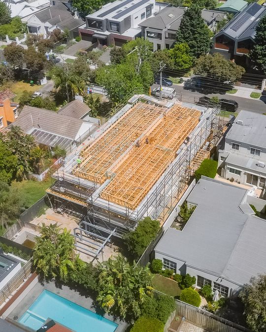 Aerial view of residential construction with exposed timber framing and scaffolding.