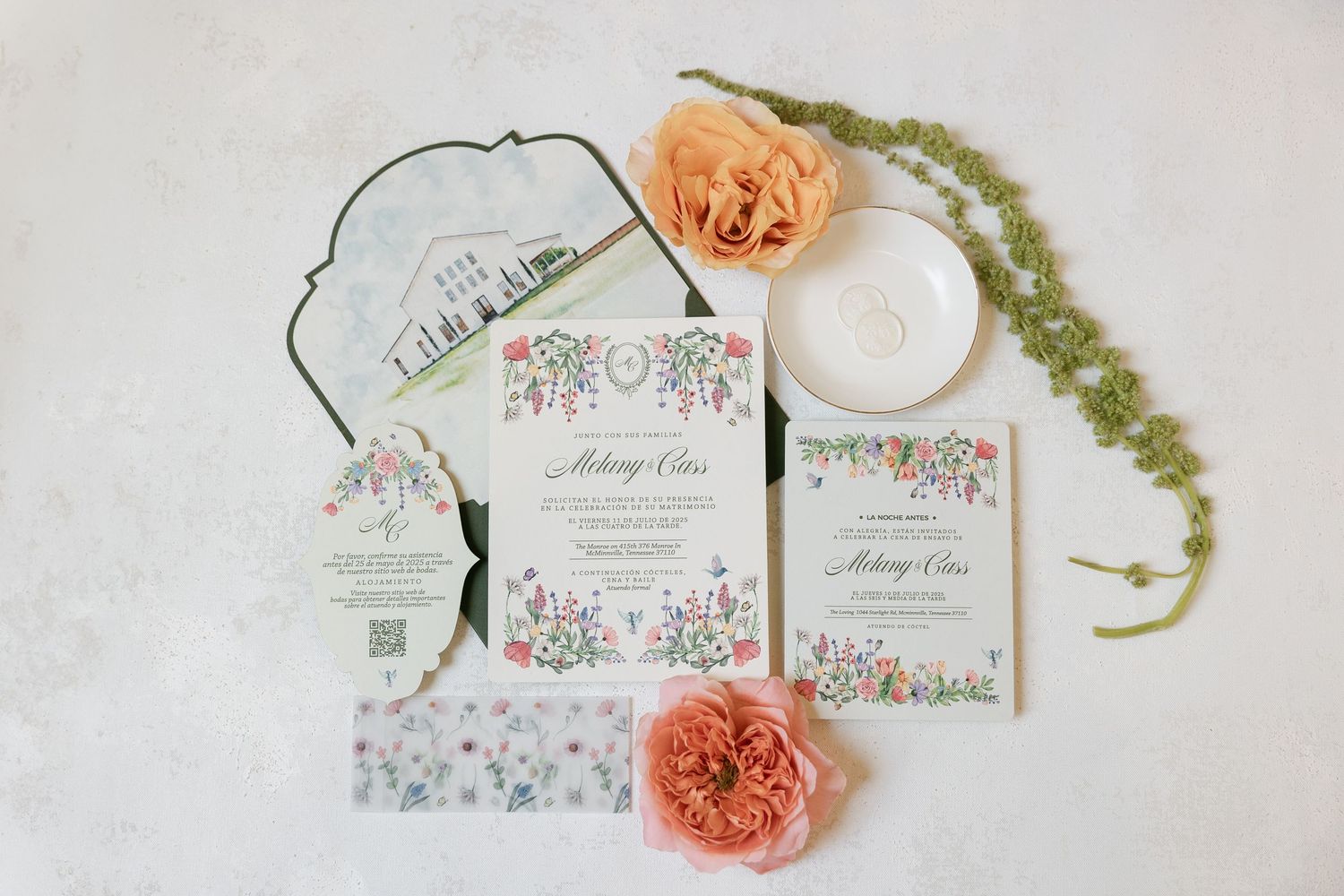 Elegant floral wedding invitation suite with peach roses and greenery arranged on white marble background.
