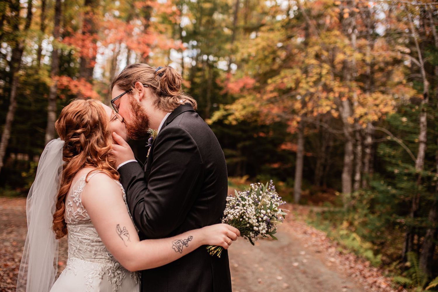 Wedding couple sharing intimate moment surrounded by autumn foliage.