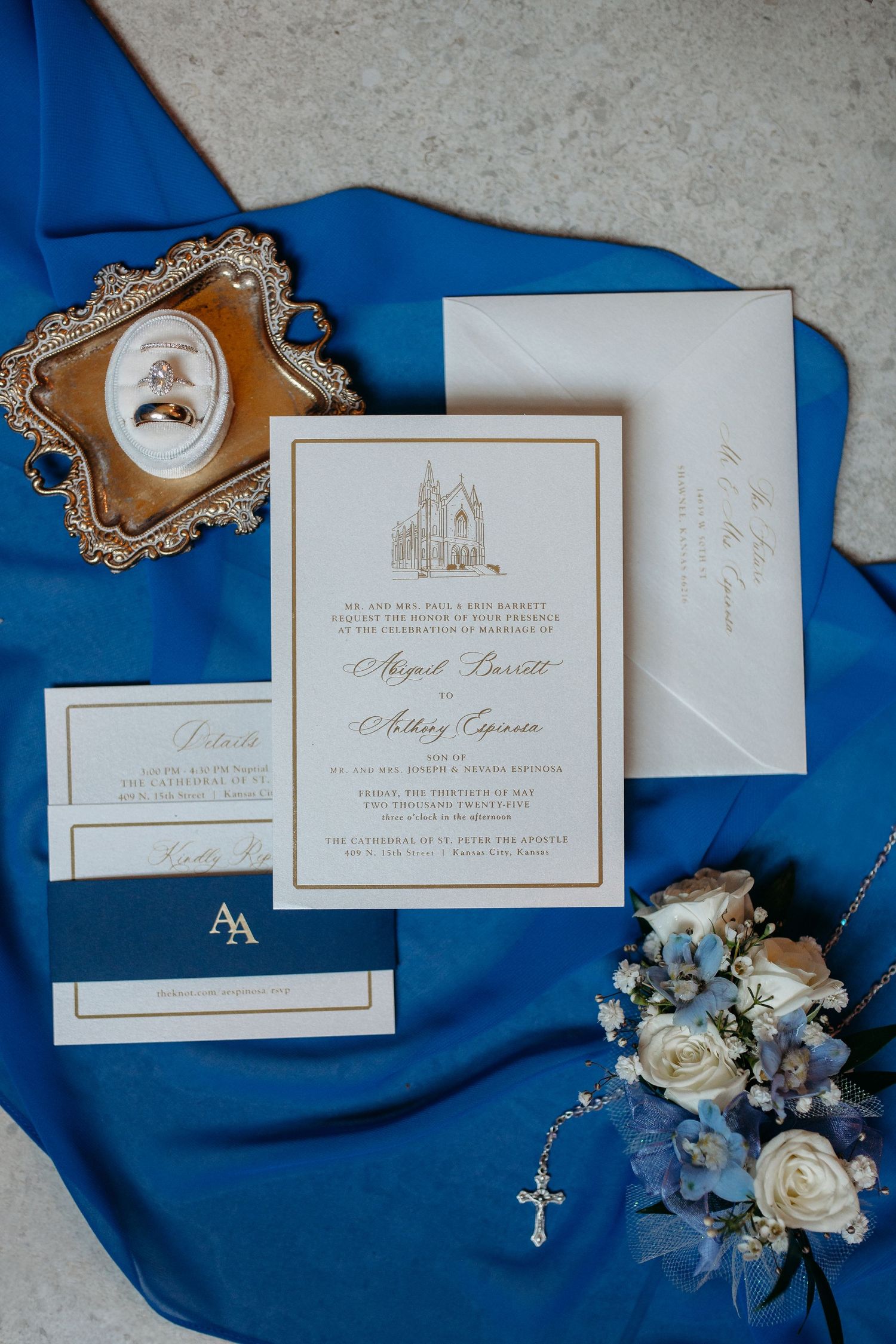 Catholic Photography Wedding invitation suite with elegant gold details and blue roses displayed on royal blue silk fabric backdrop Kansas.