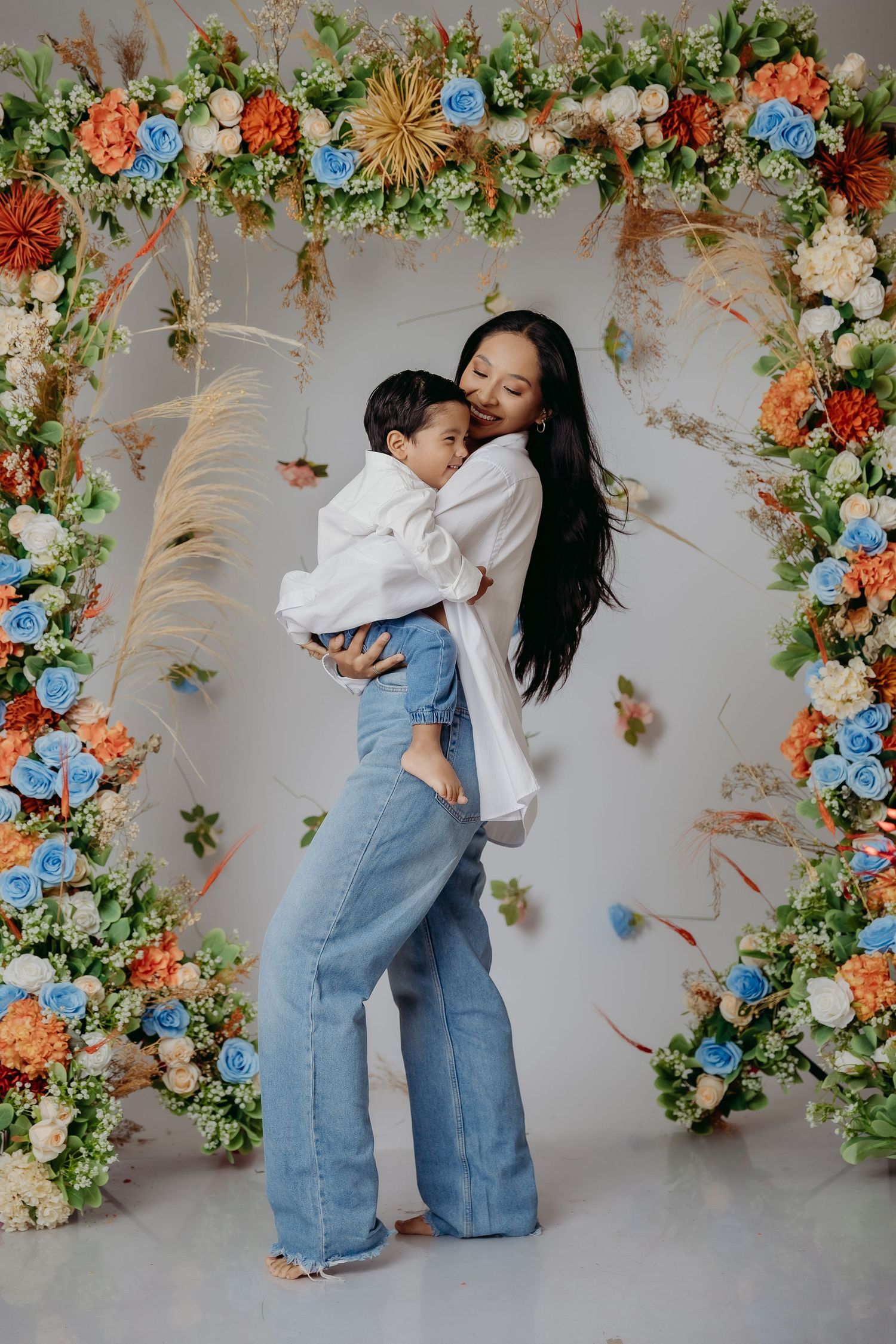 Elegant floral arch with colorful blooms and pampas grass decorations creates romantic backdrop for intimate portrait session.