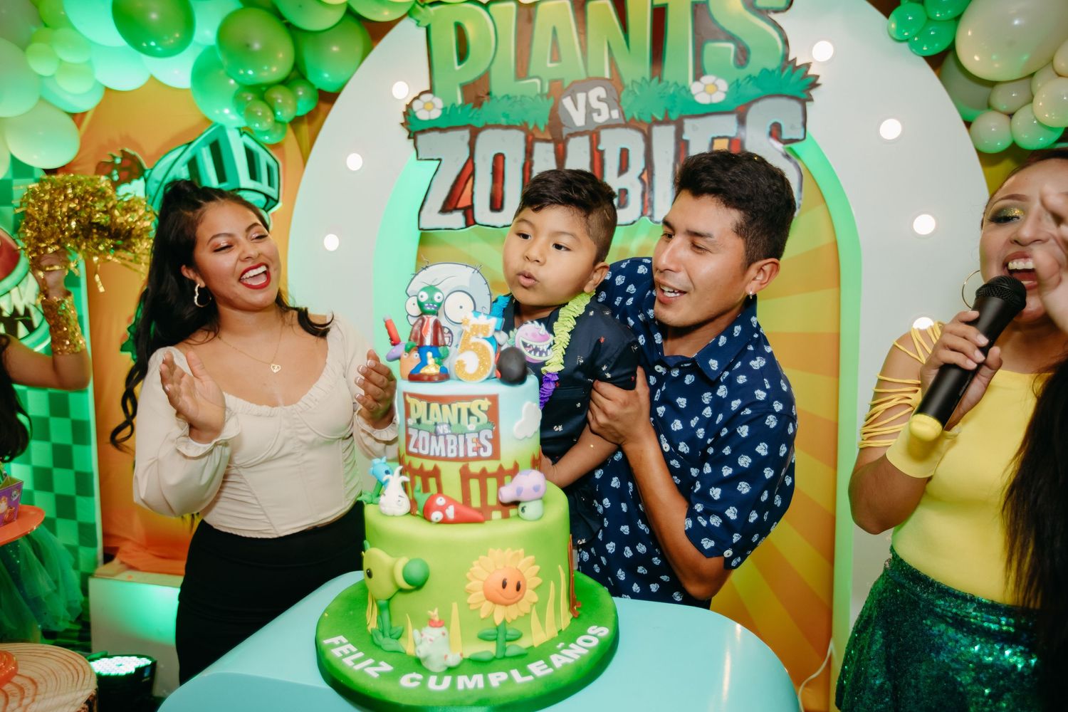 Colorful Plants vs Zombies themed birthday party with a decorated tiered cake and green balloon decorations.