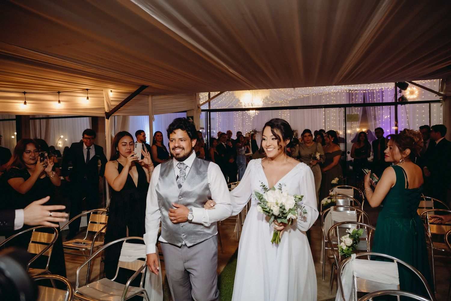 Wedding reception entrance with guests clapping and celebrating in rustic indoor venue.