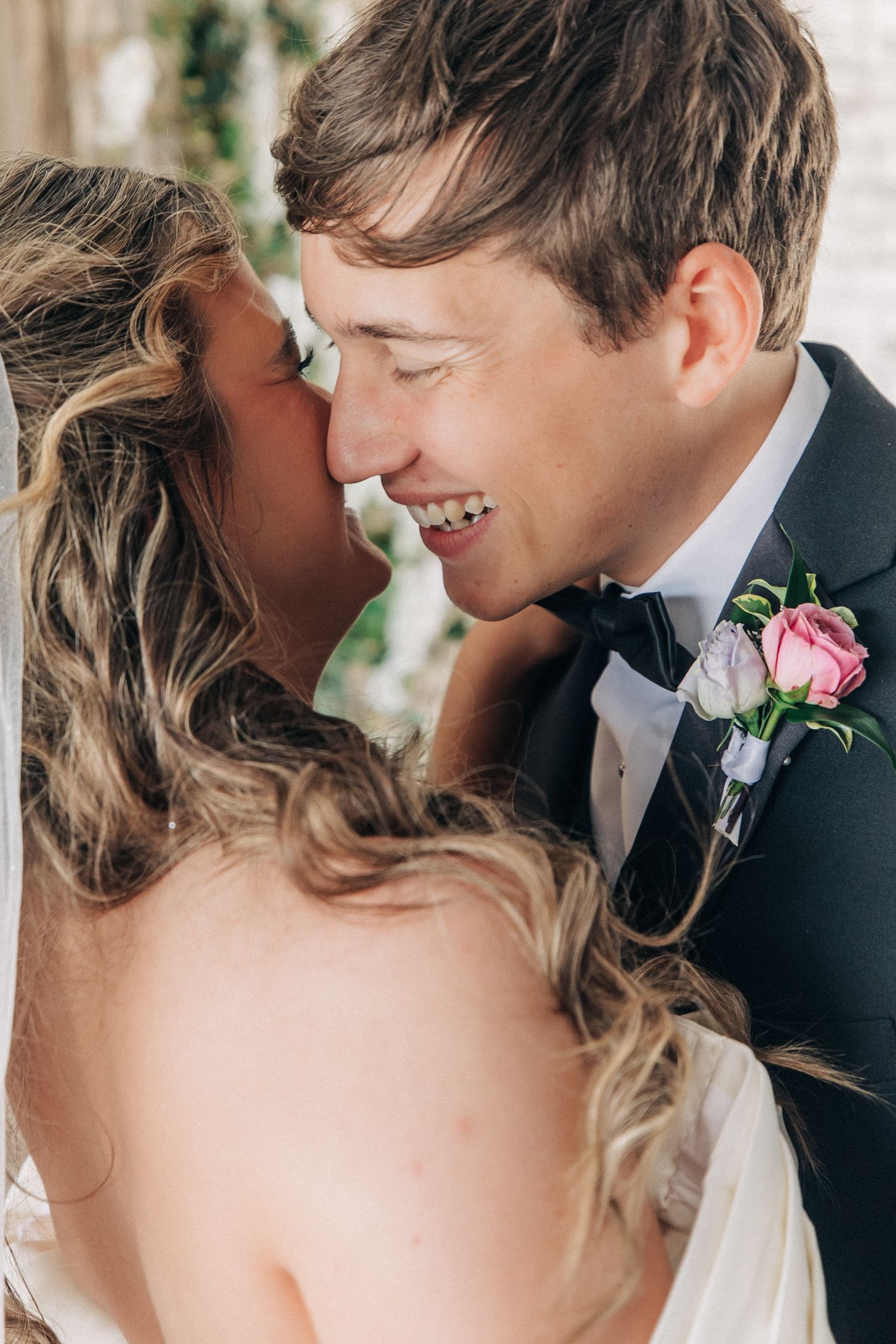 Intimate wedding portrait showing a tender moment between newlyweds, with the groom wearing a pink boutonniere.