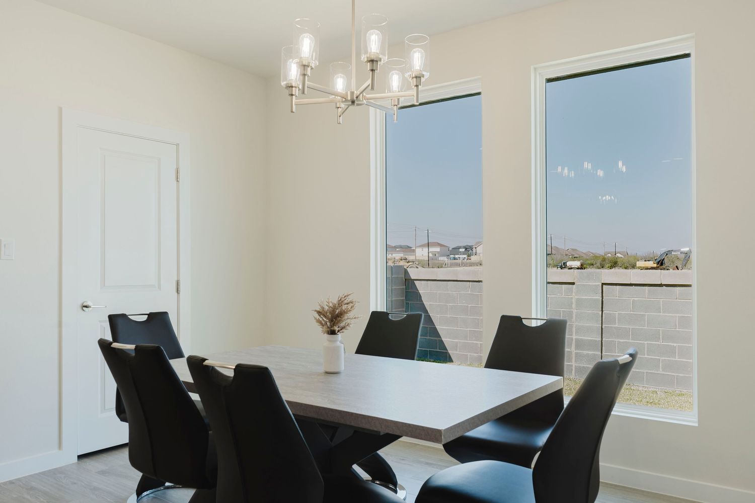 Modern dining room with black chairs, white table and large windows offering city views.