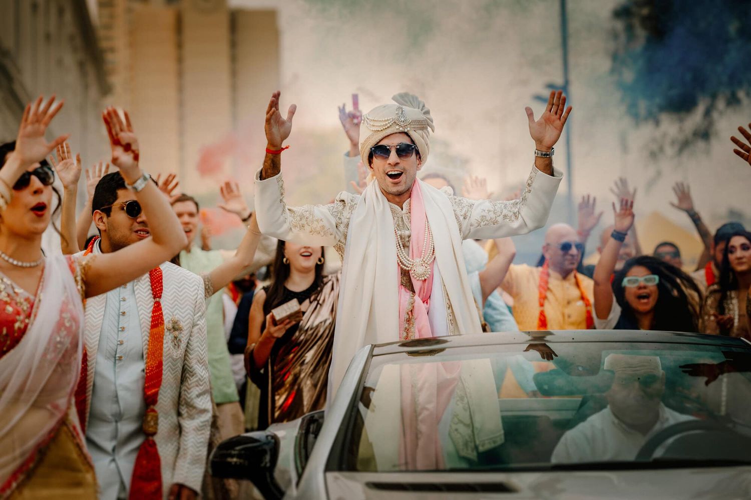 Vibrant celebration at an Indian wedding with joyful dancing and colorful powder amid festive atmosphere.