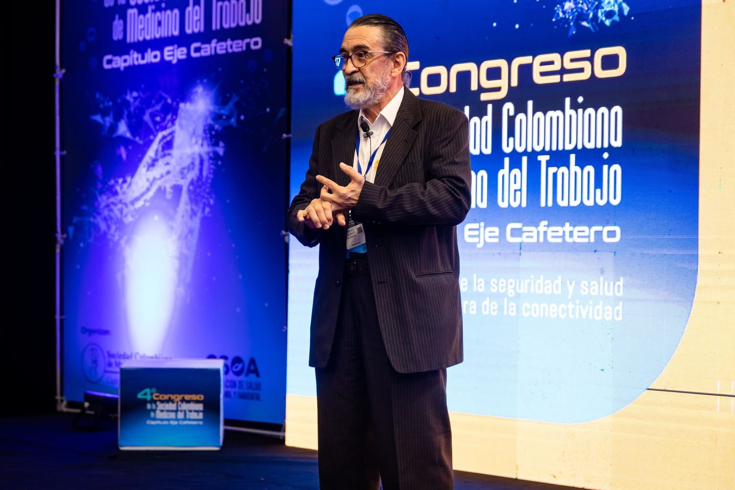 Conferencista en escenario iluminado, Congreso Colombiano de Trabajo. fotografía corporativa profesional para eventos empresariales.