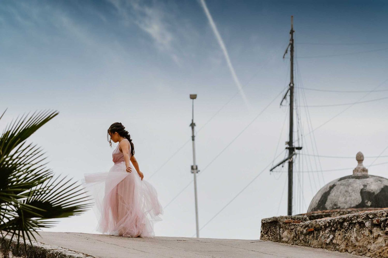 A dreamy bridal portrait shoot featuring a flowing pink wedding dress against a scenic coastal backdrop.