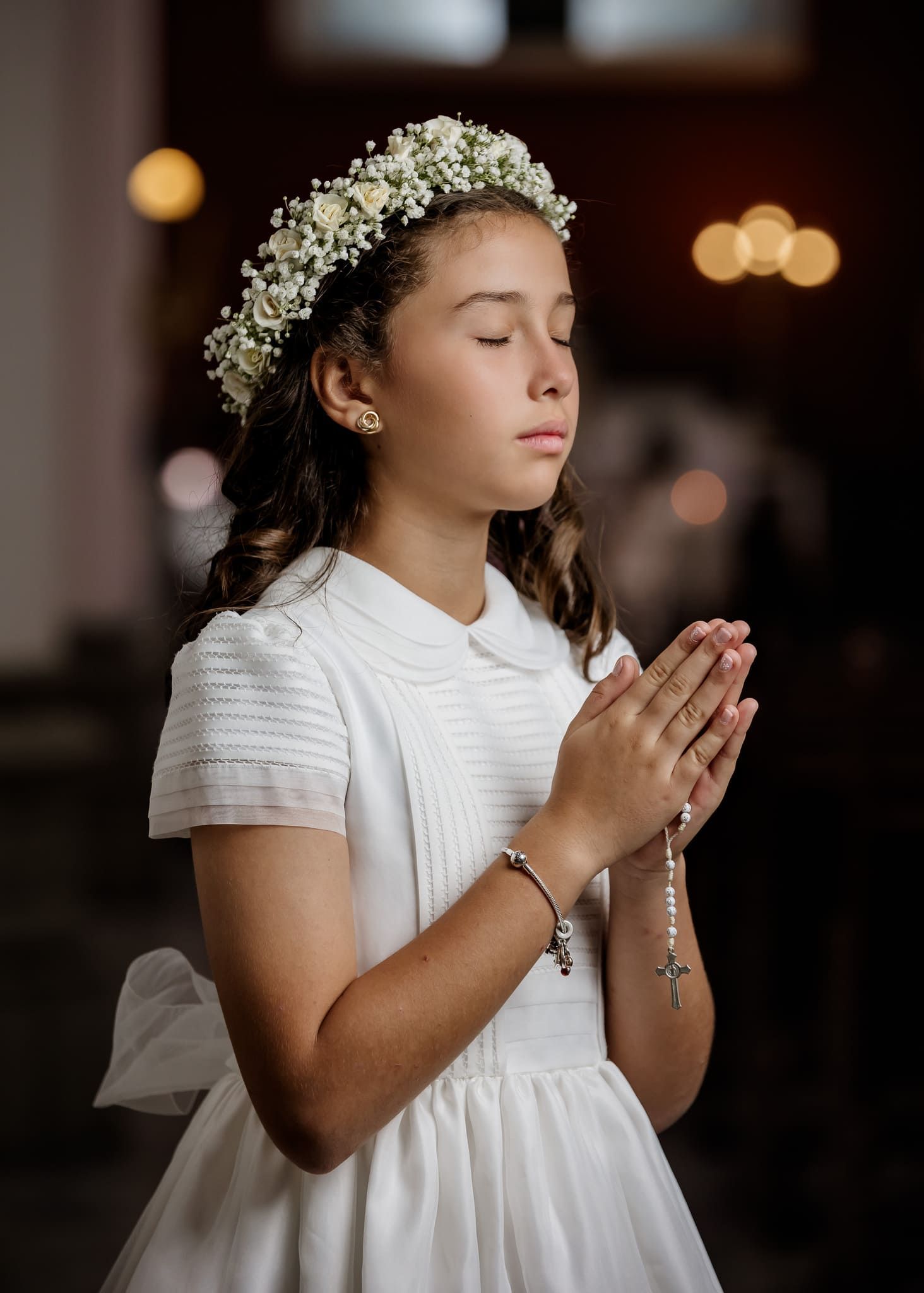 foto de primera comunion retrato de nina orando con corona de flores en iglesia
