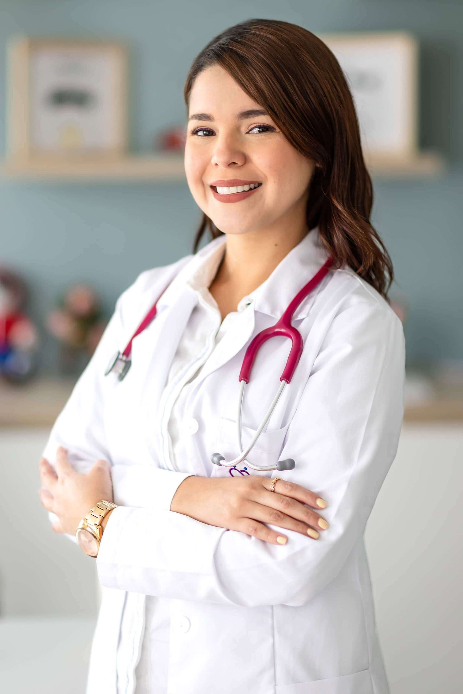 Healthcare professional in white coat with stethoscope smiling in medical office setting.