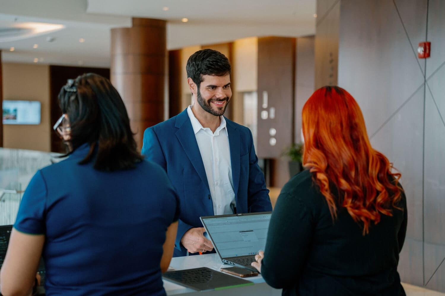 Business professionals interact in a modern office hallway during a meeting discussion.