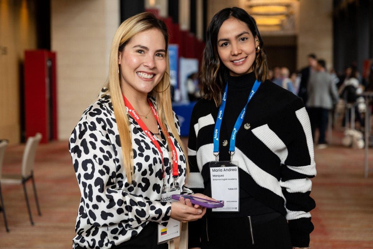 Two colleagues networking at a conference wearing name badges, one in leopard print and one in black and white stripes.
