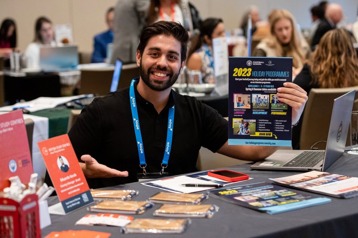 A vendor displays promotional materials and books at their table during a convention or trade show.