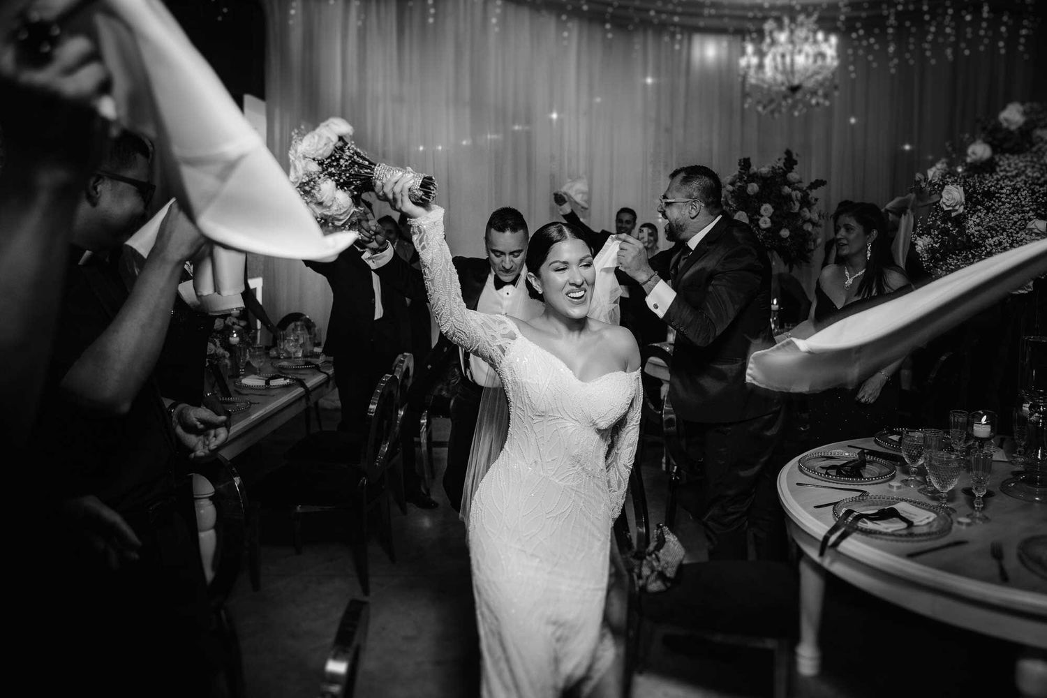 Novia celebrando sonriente en la recepción de la boda en blanco y negro.