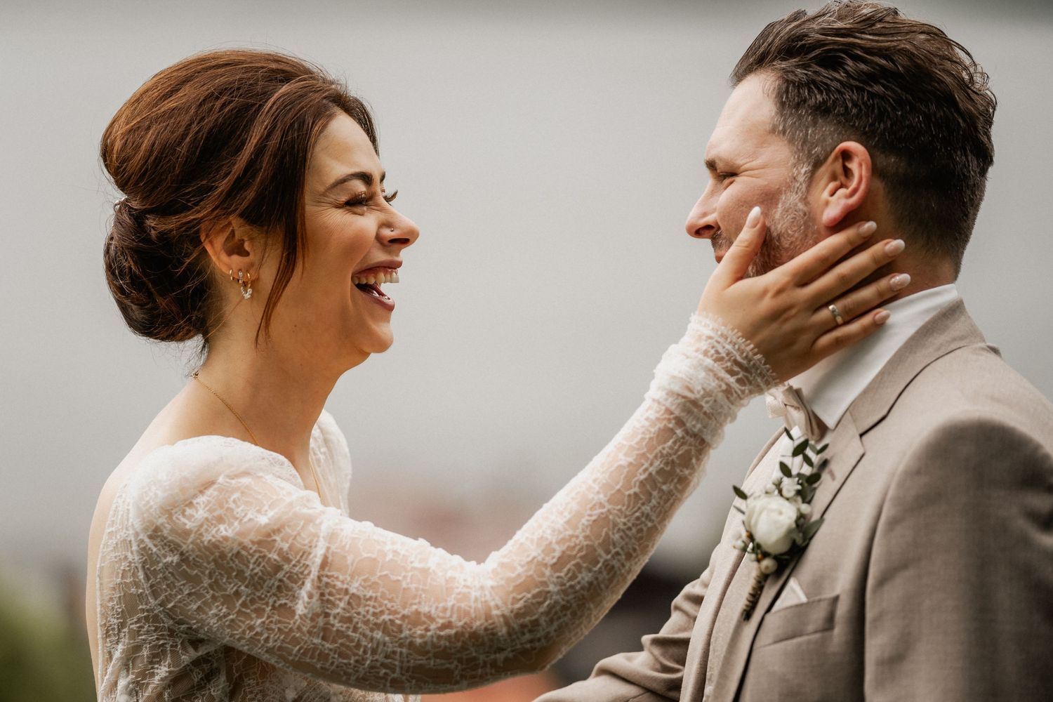 A joyful intimate moment between newlyweds as they share laughter together during their wedding day photography session.