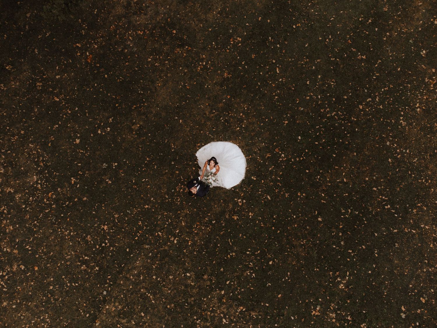 Aerial view of a white ceramic toilet on a speckled brown surface surrounded by scattered debris.