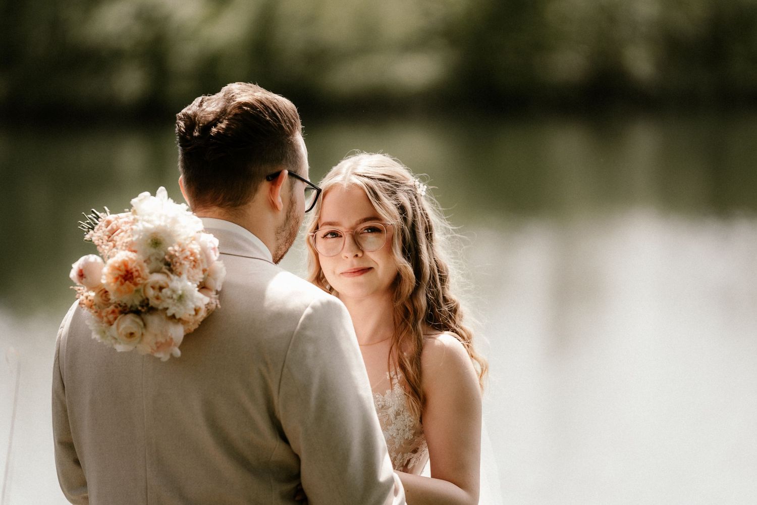 A romantic wedding couple shares intimate moments in a series of black and white photographs by a lake.