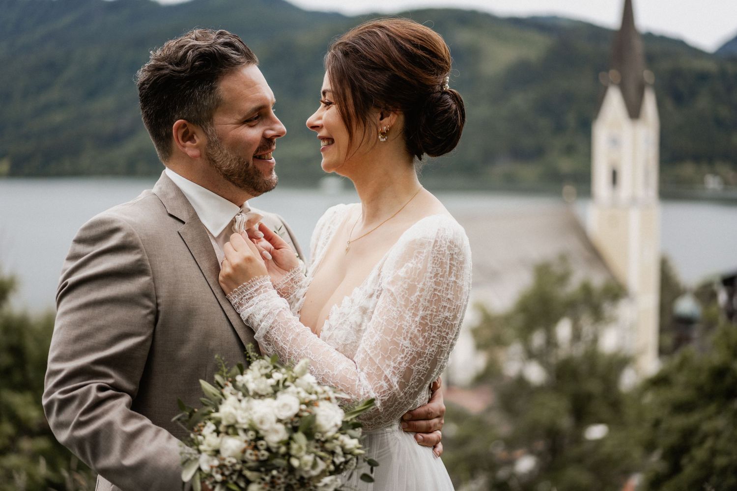 A romantic wedding couple shares an intimate moment in their wedding attire against a scenic mountain backdrop.