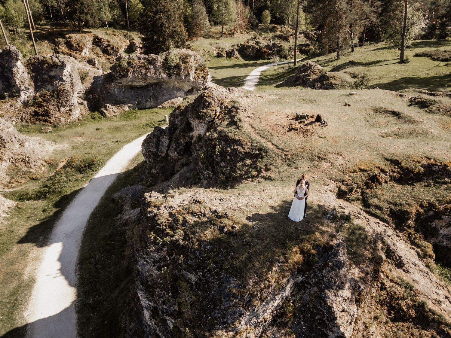 Curved white pathway through rocky desert landscape with tall rock formations on sides.