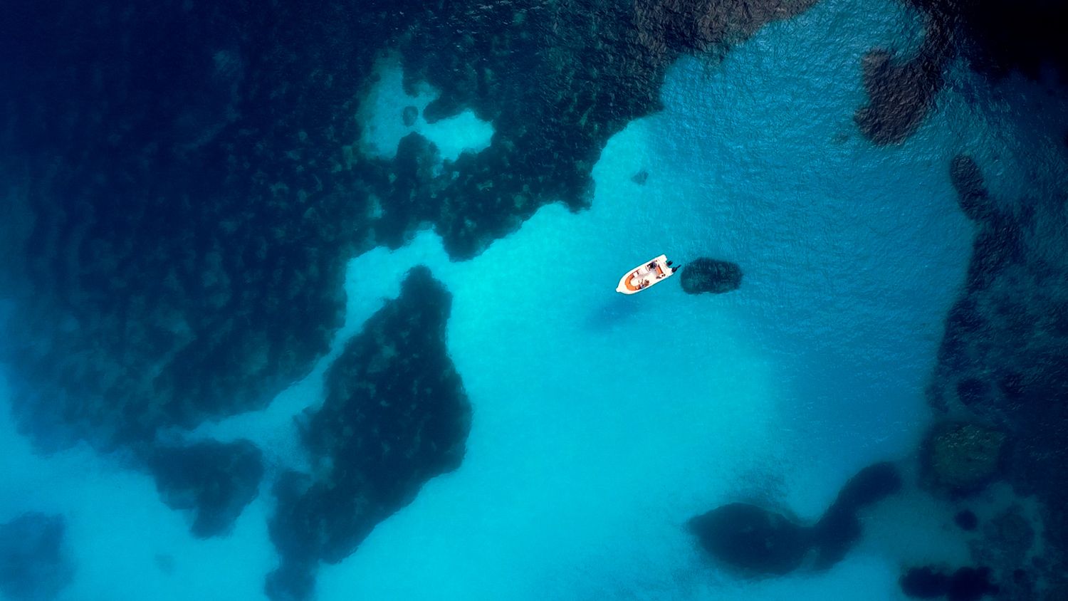 White boat froating on a crystal clear blue water in Greece