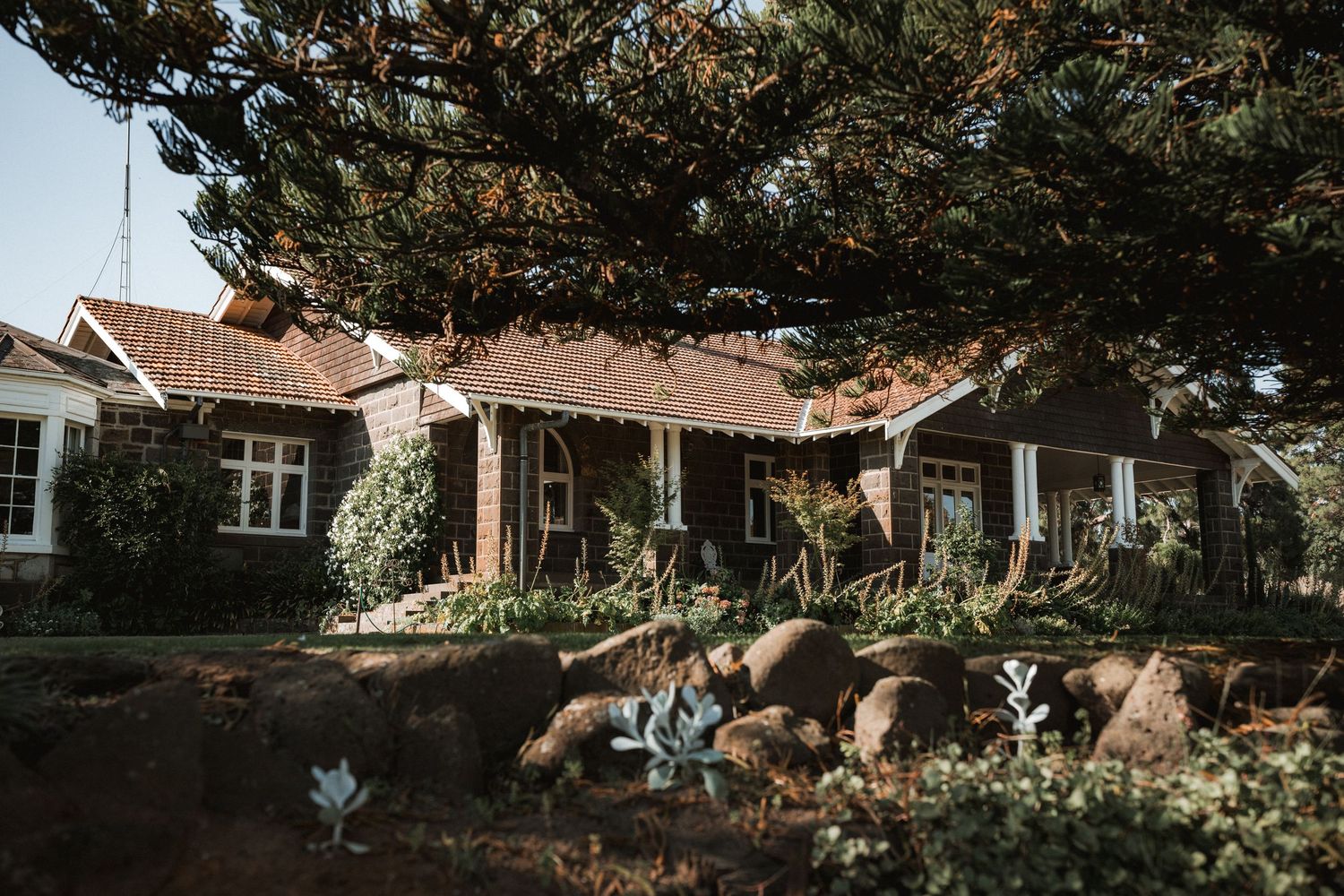 A charming coastal cottage with rustic landscaping and natural stone features.