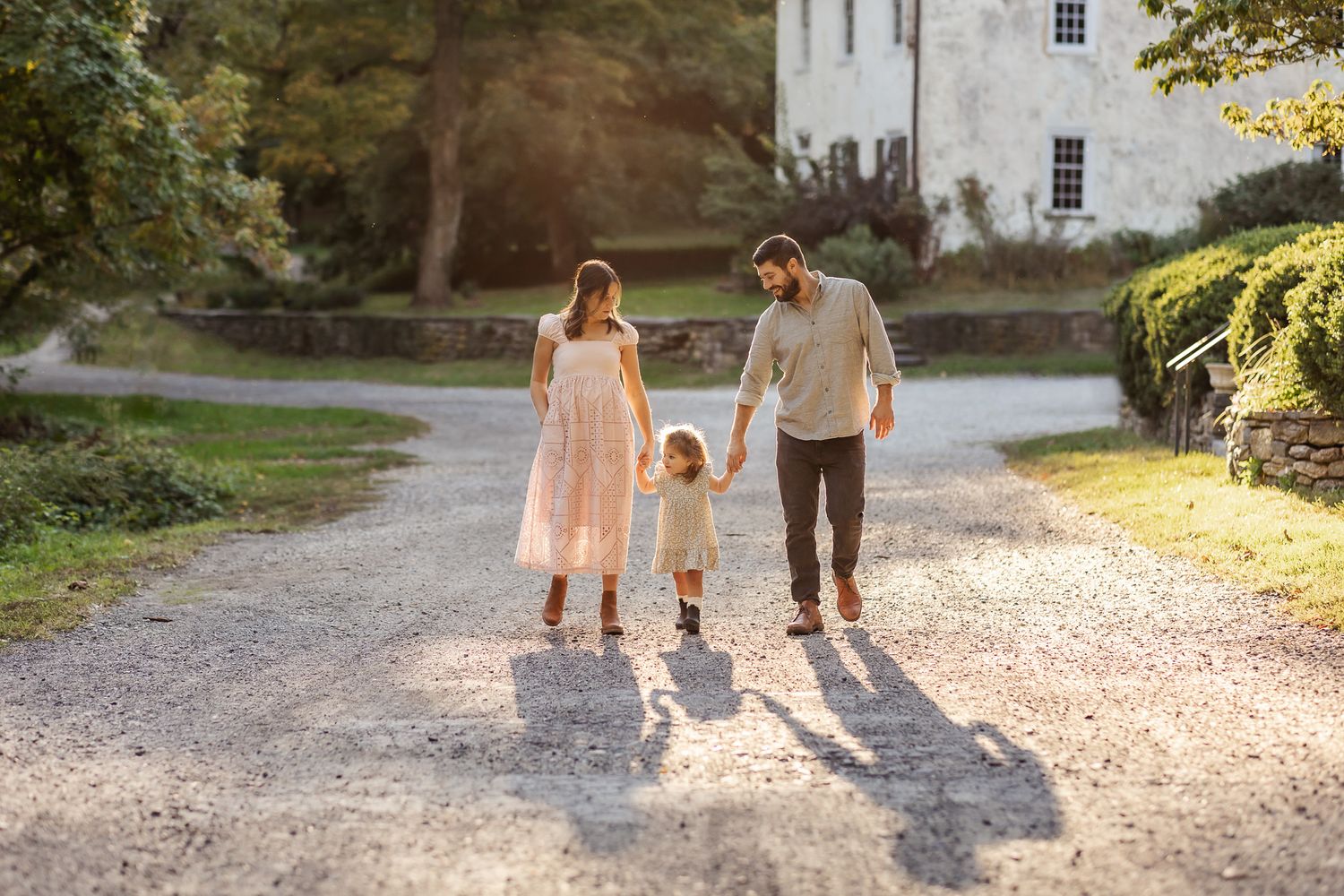 Parents hold hands with little girl while walking in Rittenhousetown