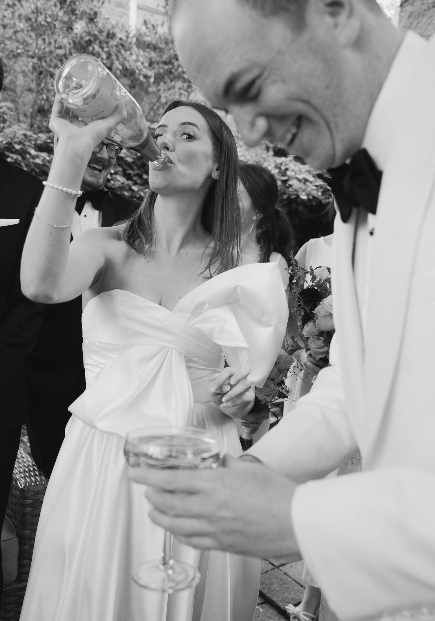 Couple celebrating at a wedding reception with champagne glasses in an elegant black and white photograph.