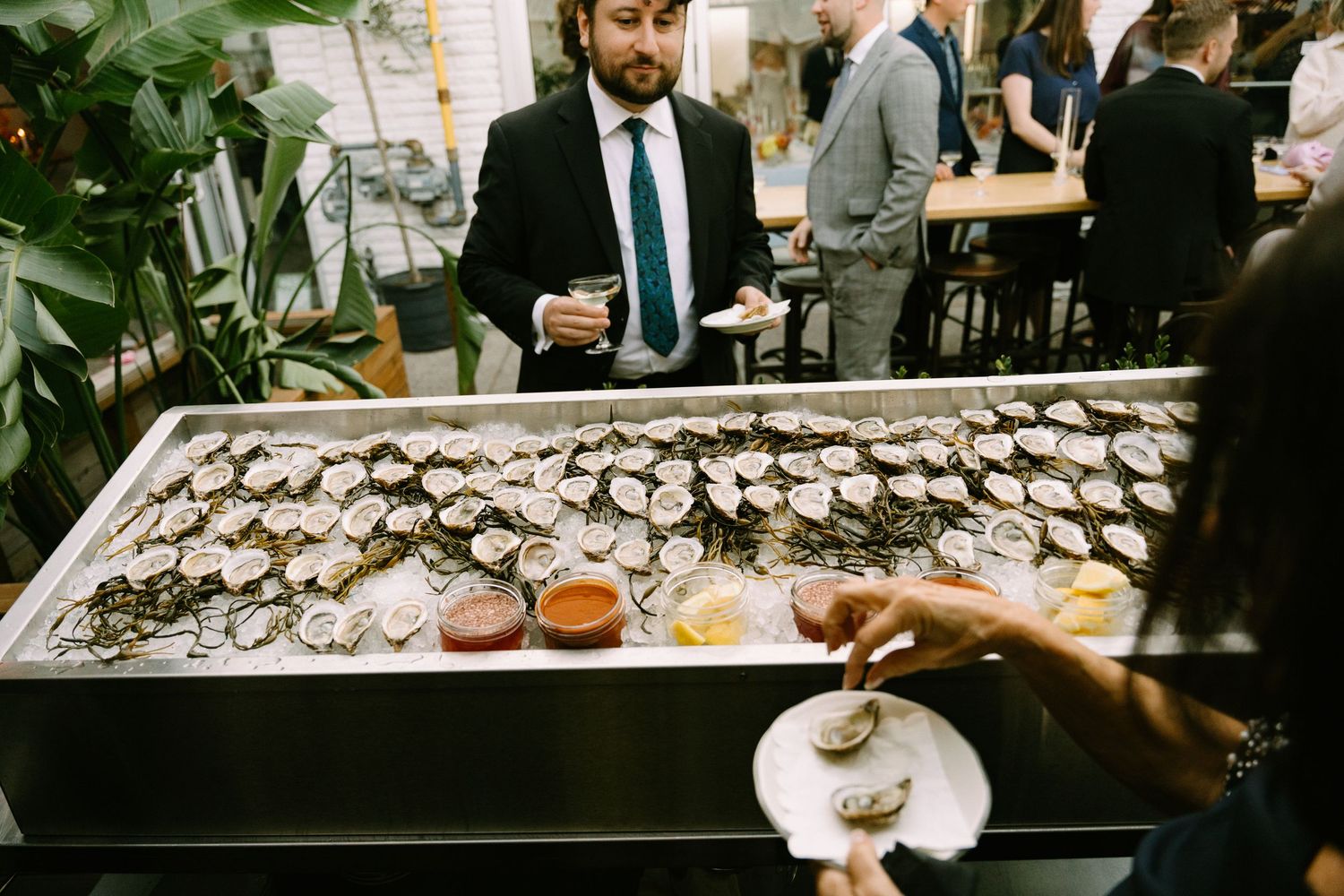 Fresh oysters on ice being served at an elegant restaurant event with a business-attired person in the background.