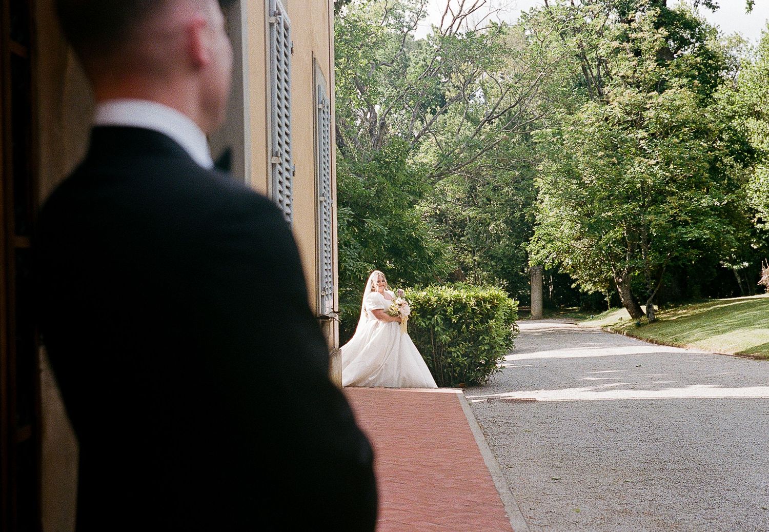 A panoramic view of a tree-lined outdoor wedding venue pathway.