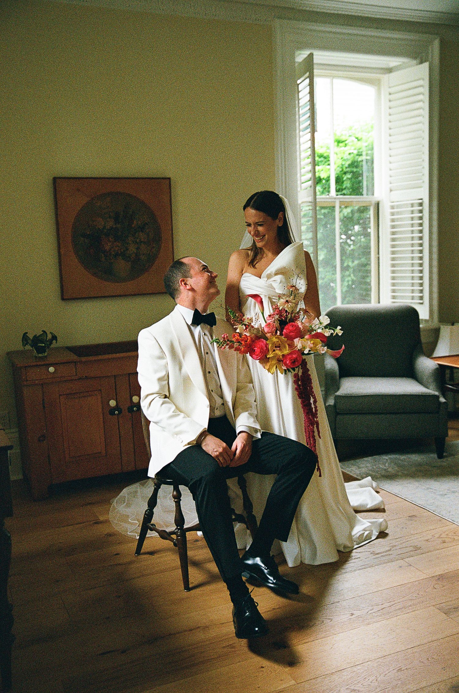 A series of four connected photos showing a couple interacting in traditional white and black formal attire in a sunlit room.