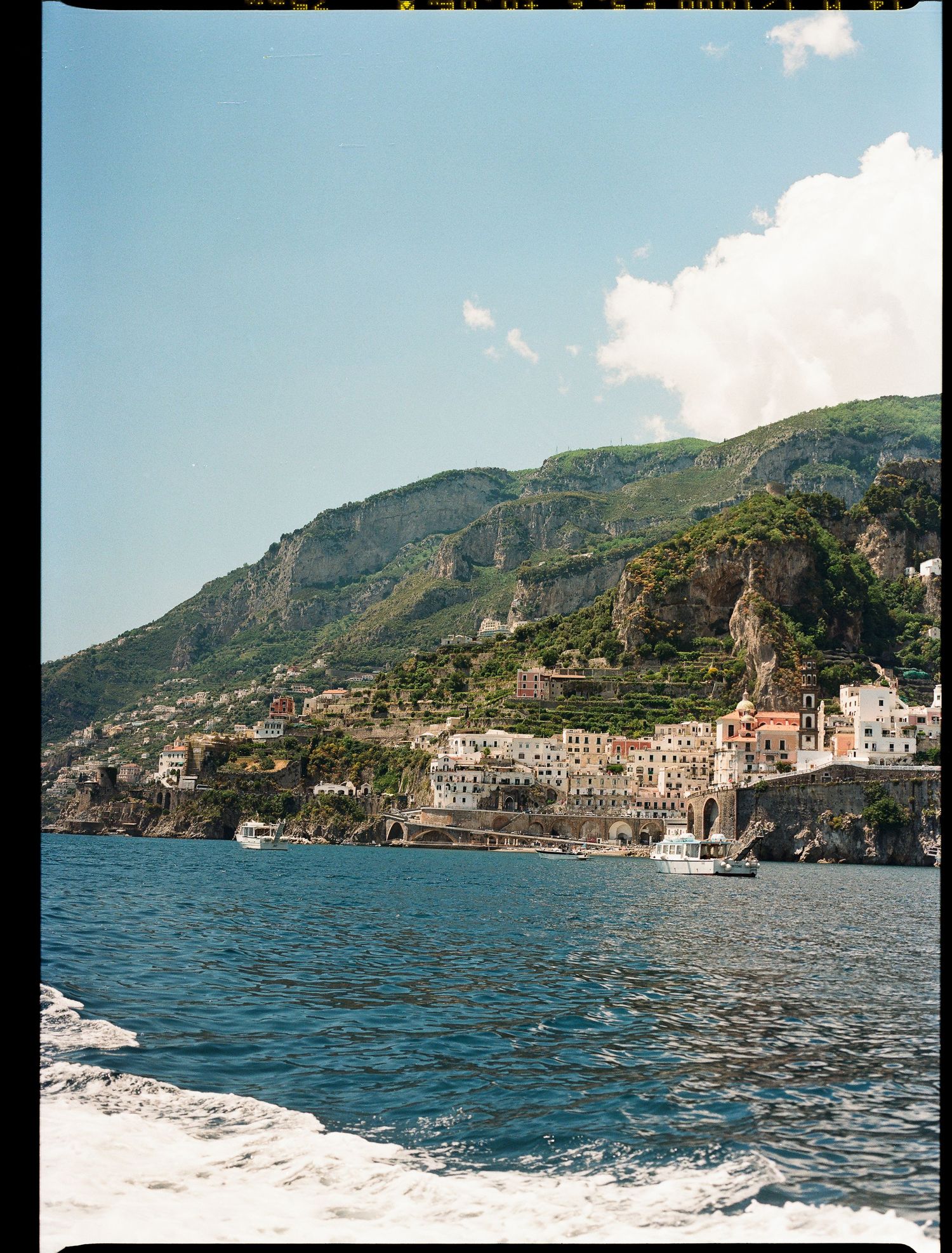 Scenic coastal view of Amalfi Coast in Italy with historic buildings nestled against steep cliffs along blue Mediterranean waters.
