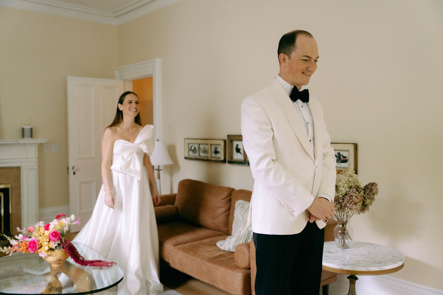 A formal wedding scene with classic decor and elegant attire in a light-filled room.
