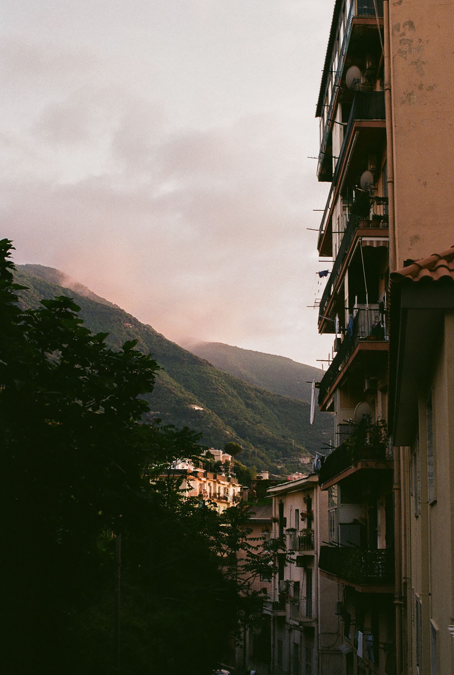 Moody sunset view of mountain village buildings with balconies and narrow alleyway in European mountain town.