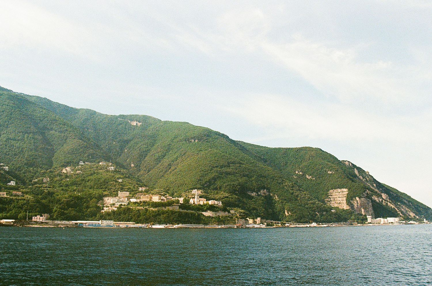 Coastal view of Amalfi Coastline. Mountainous landscape with scattered buildings along the Mediterranean shoreline.