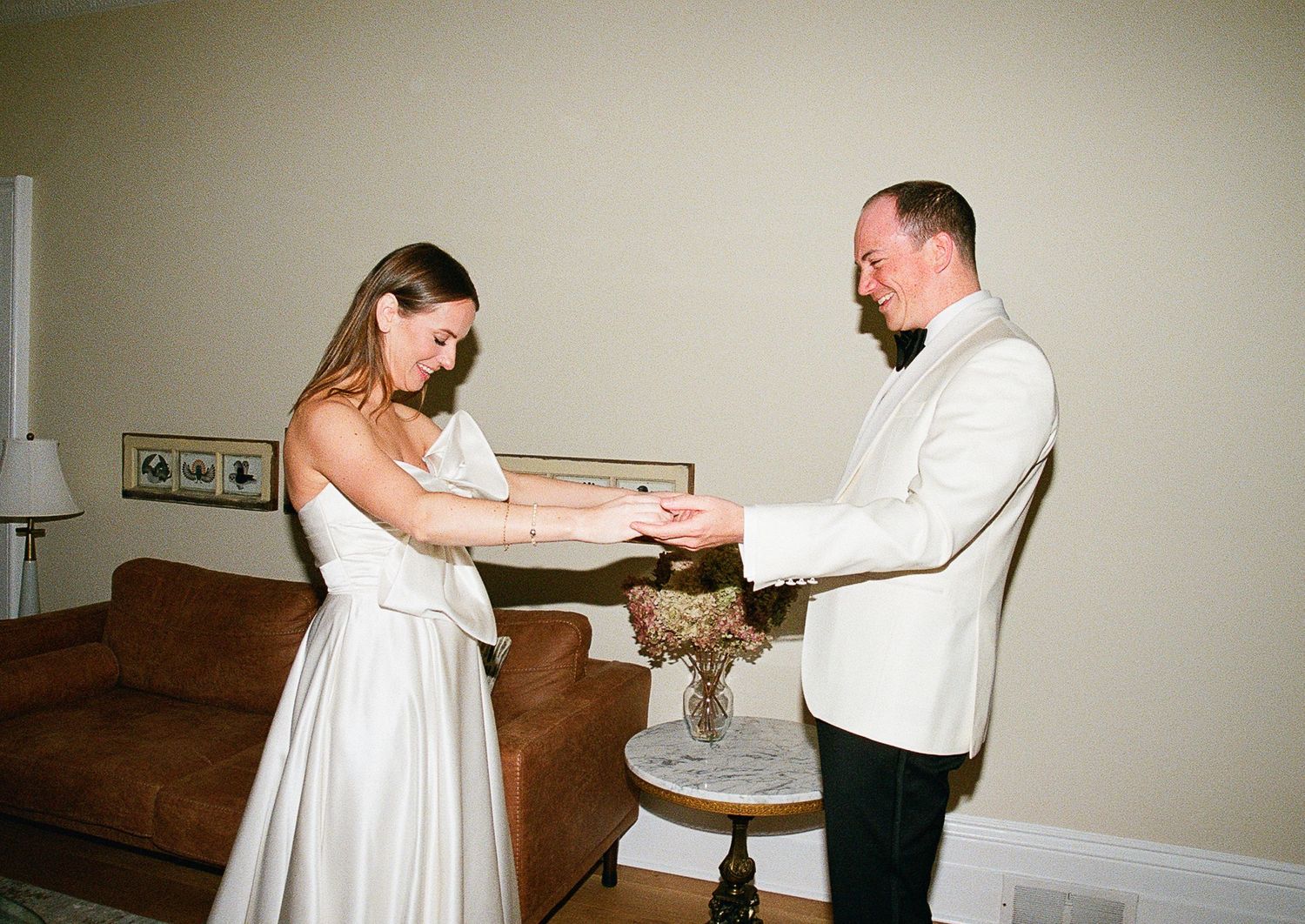 A couple in wedding attire cutting their cake together at a small indoor reception.