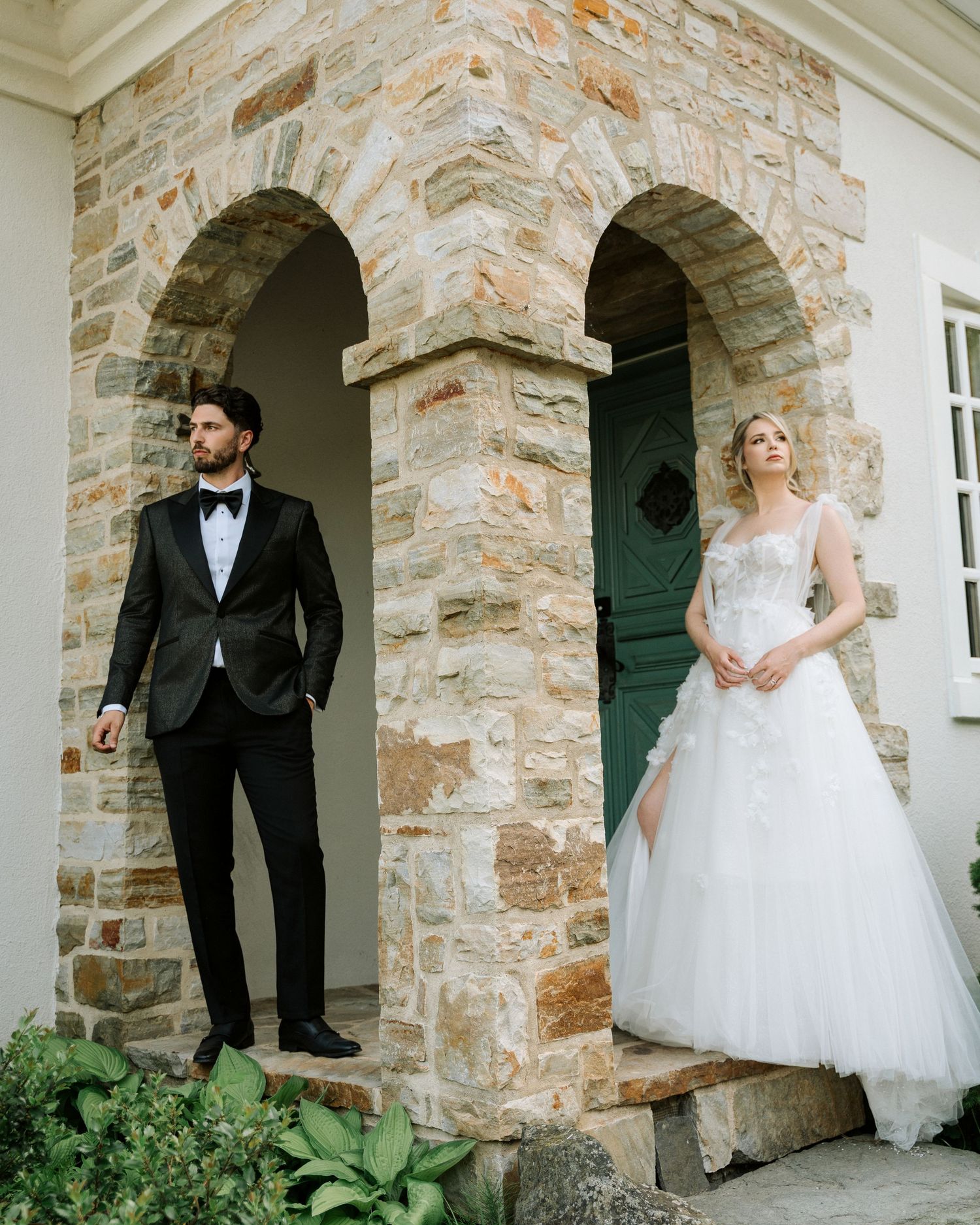 Stone archway entrance of an elegant building with wedding couple in formal attire.