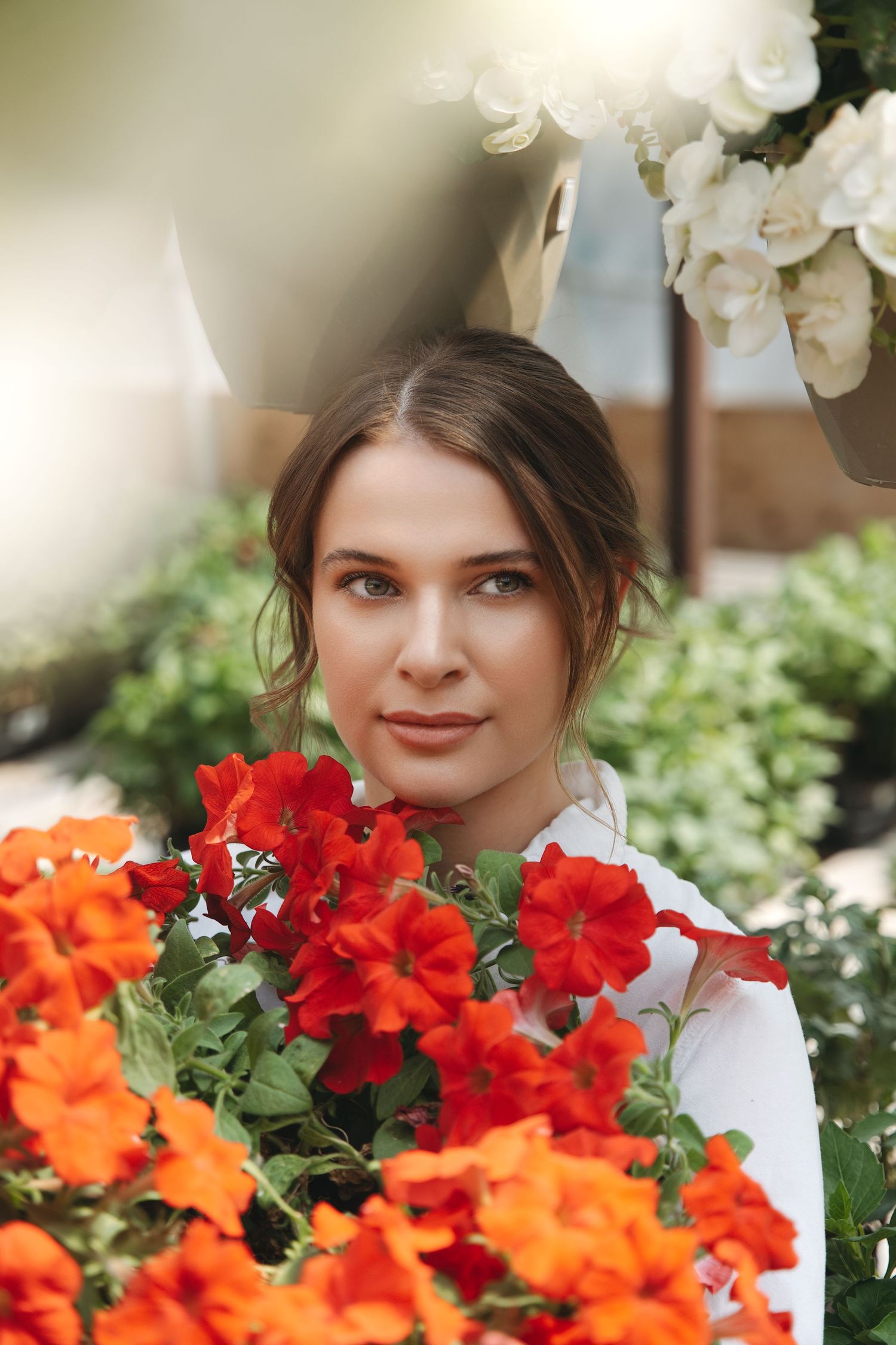 A close-up portrait amidst vibrant orange and red flowers in a garden setting.