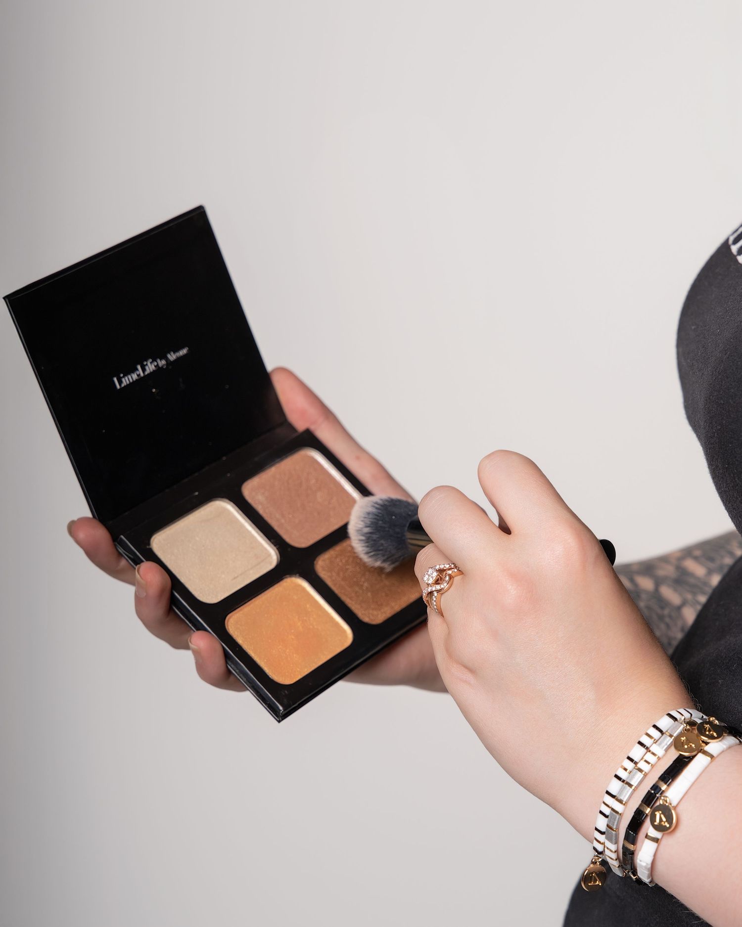 Hands demonstrating makeup application with compact powder and brushes.