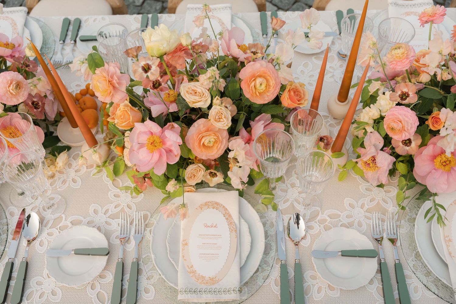 Elegant wedding reception table setting with pink and peach floral centerpieces and crystal glassware.