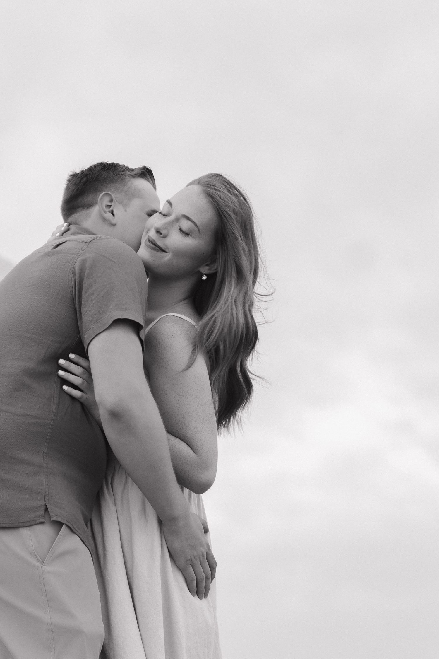 A romantic couple in love sharing an intimate kiss while embracing each other in black and white photography.