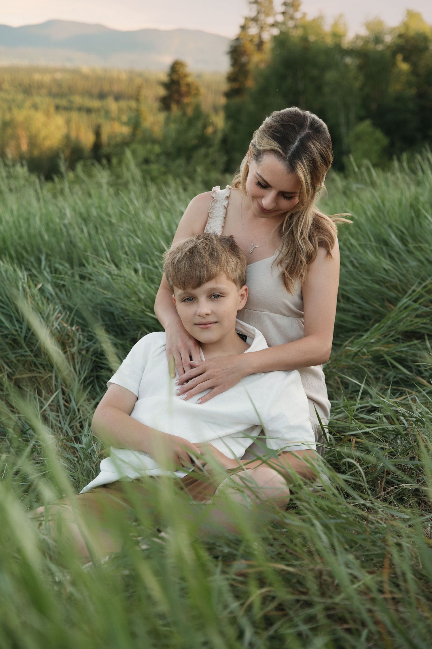 Intimate family moment captured in long grass during golden hour.