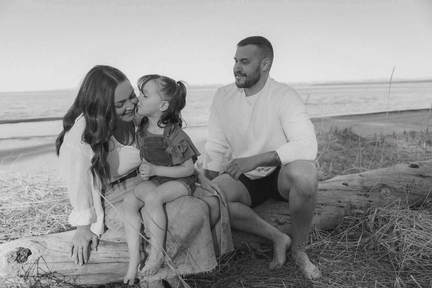 Black and white photo of a family sharing a tender moment on a hillside.