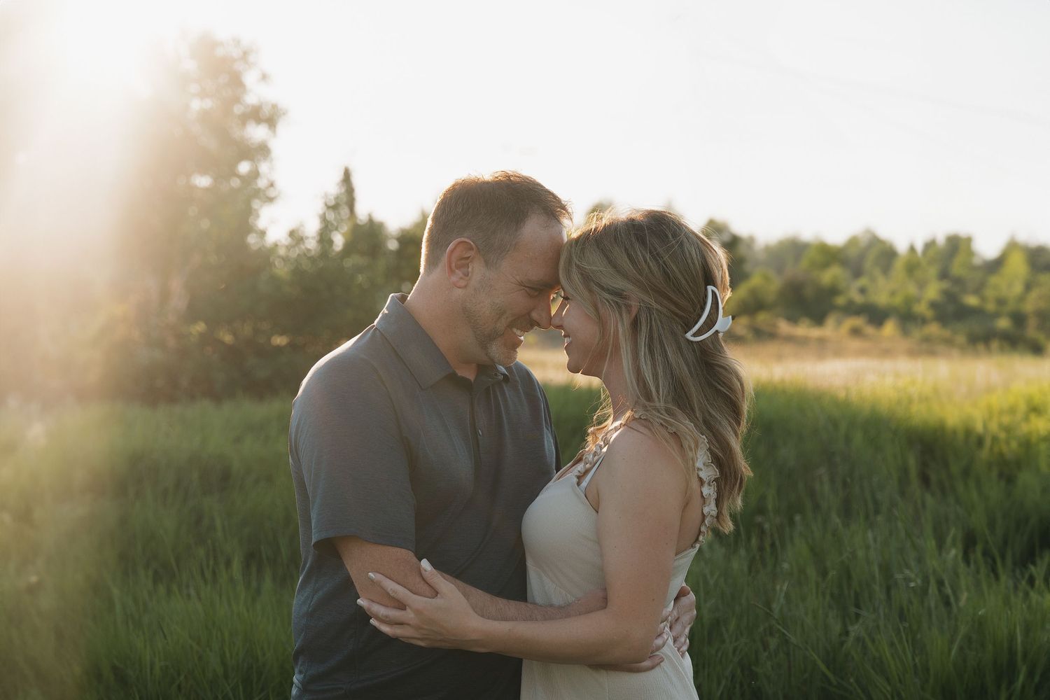 Golden hour couples photography in a serene meadow with glowing backlight.