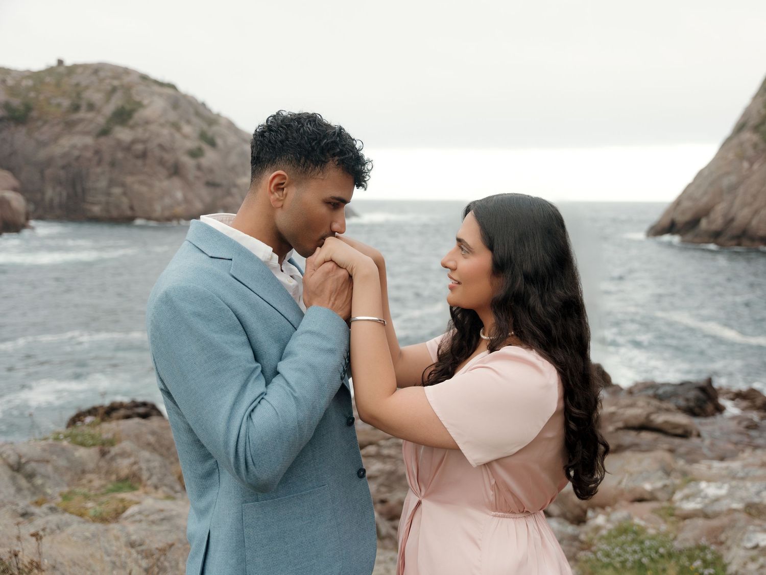 A romantic moment between a couple on rocky coastal cliffs.