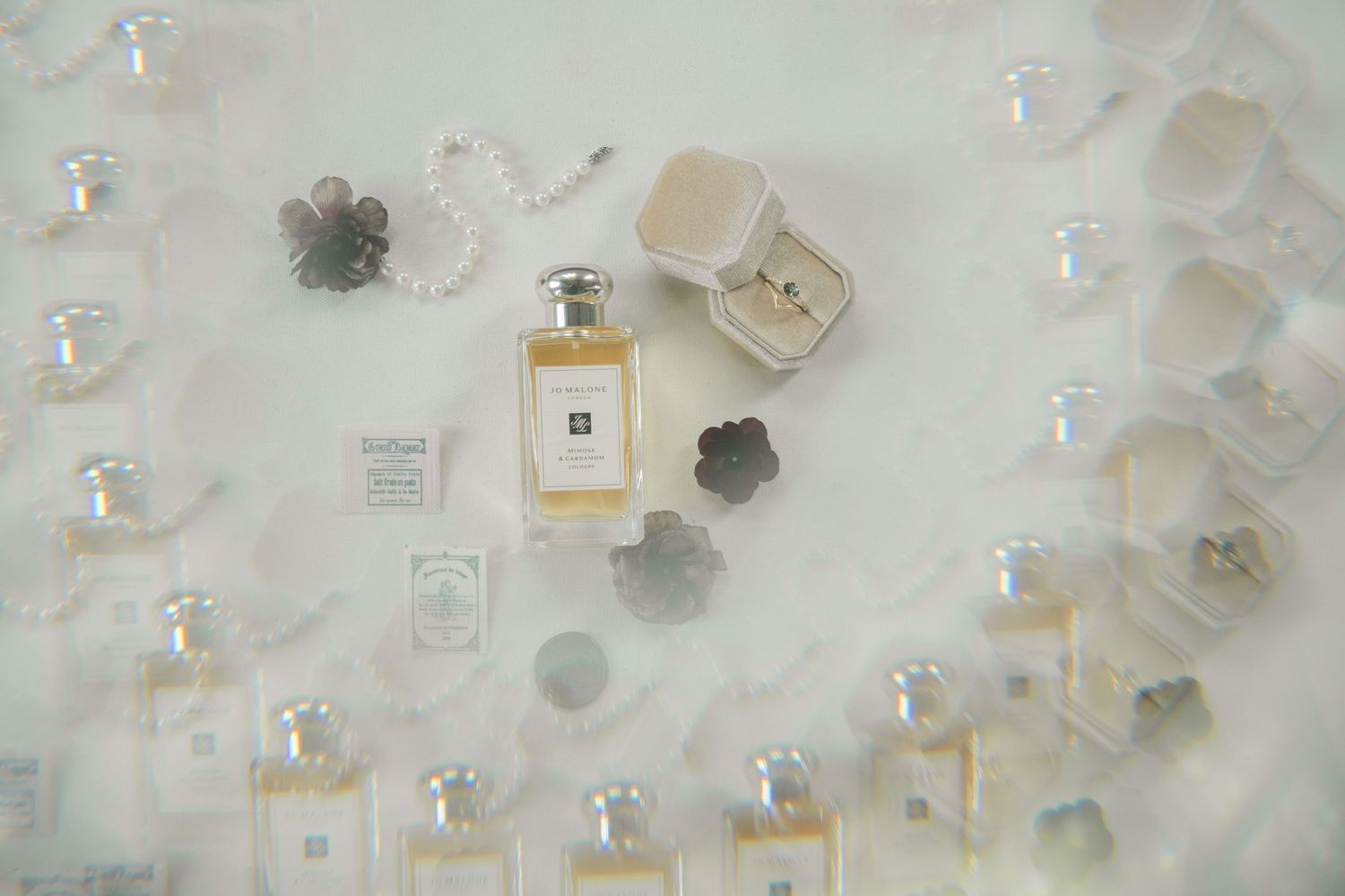 Collection of perfume bottles and cosmetic samples arranged on white surface.