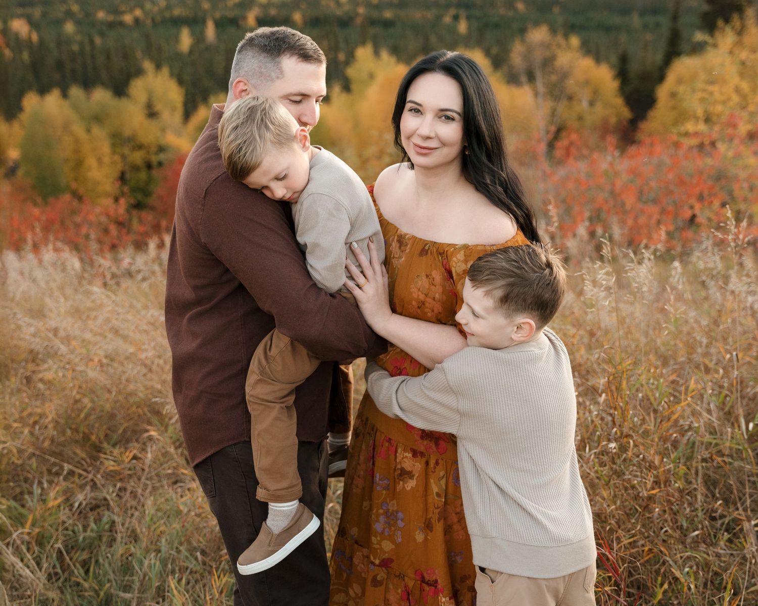 A family embracing outdoors with vibrant autumn foliage in the background.